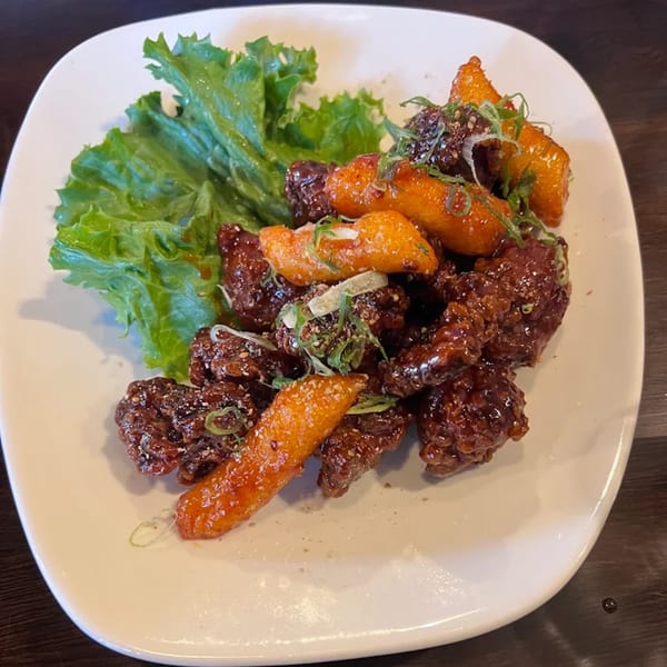Baekga's Korean fried chicken and tteokbokki, garnished with green onions and sesame seeds.