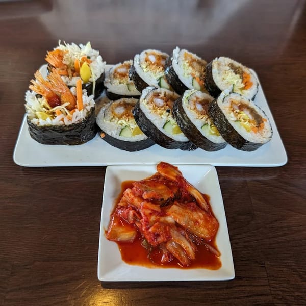 Baekga's Korean gimbap rolls with shrimp and vegetables, served with a side of kimchi.