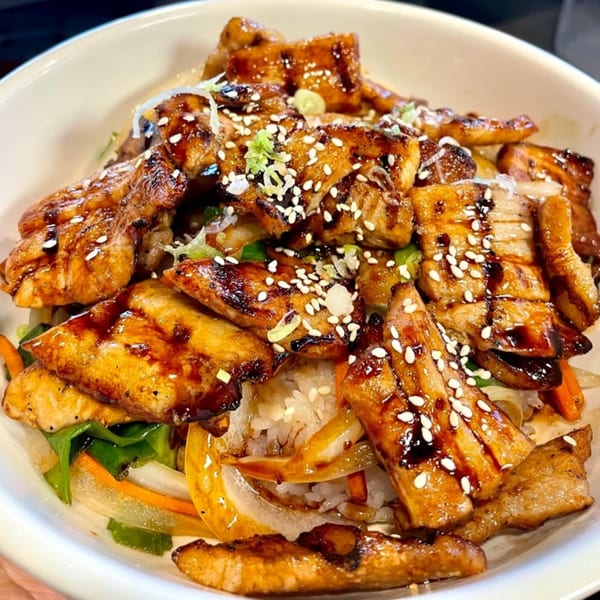 Close-up of Baekga's Korean BBQ chicken and vegetables over rice, garnished with sesame seeds.